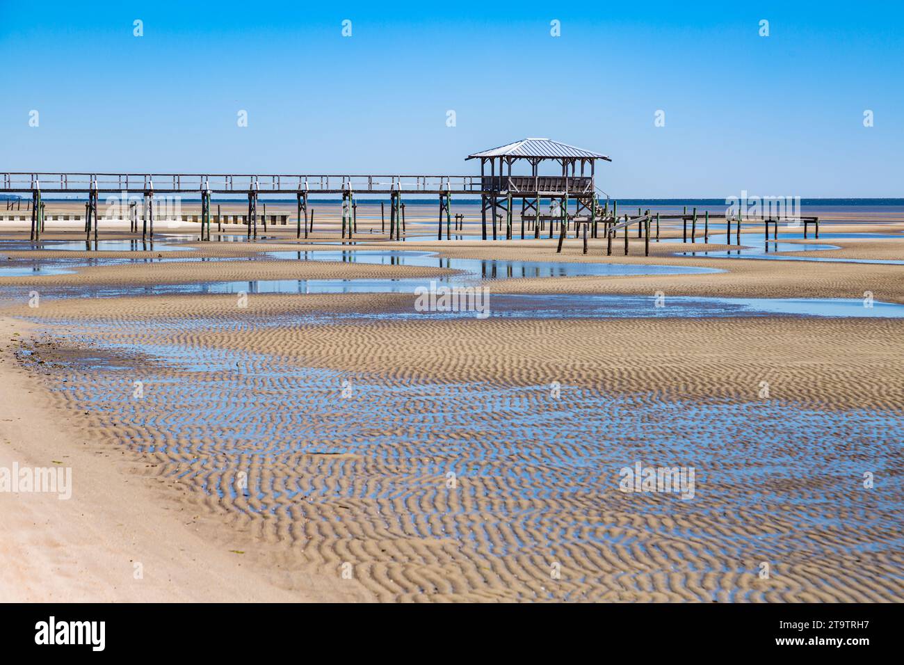 Vieux quai en bois délabré, hangar à bateaux, et jetée se dresse au-dessus des piscines de marée sur la plage de Waveland, Mississippi à marée basse. Banque D'Images