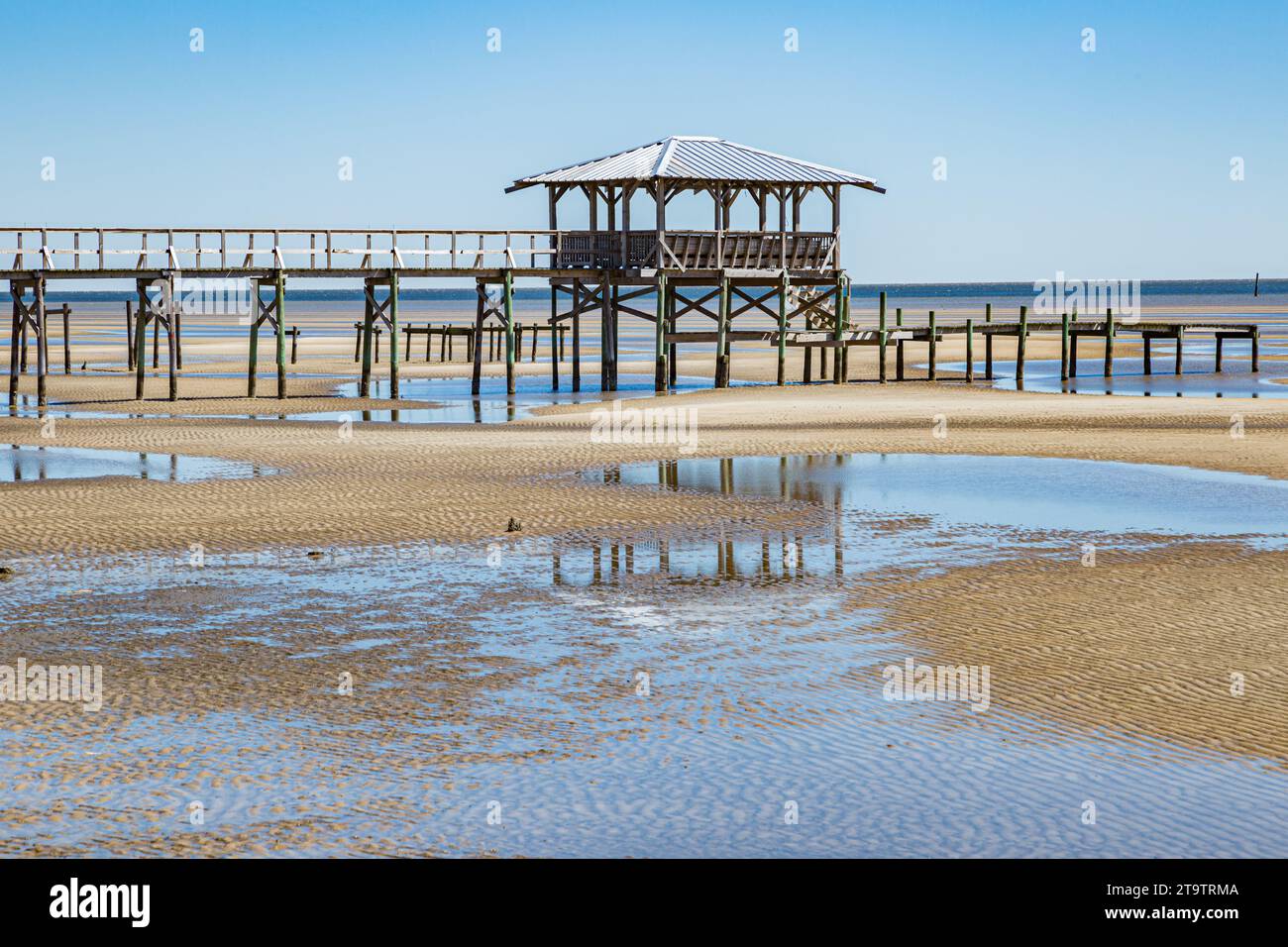 Vieux quai en bois délabré, hangar à bateaux, et jetée se dresse au-dessus des piscines de marée sur la plage de Waveland, Mississippi à marée basse. Banque D'Images