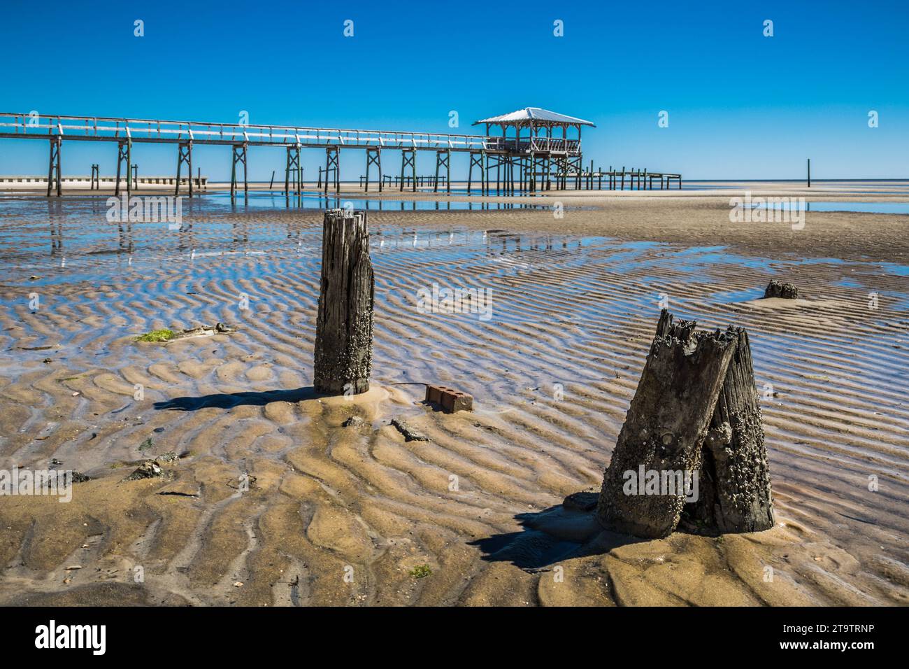 Vieux quai en bois délabré, hangar à bateaux, et jetée se dresse au-dessus des piscines de marée sur la plage de Waveland, Mississippi à marée basse. Banque D'Images