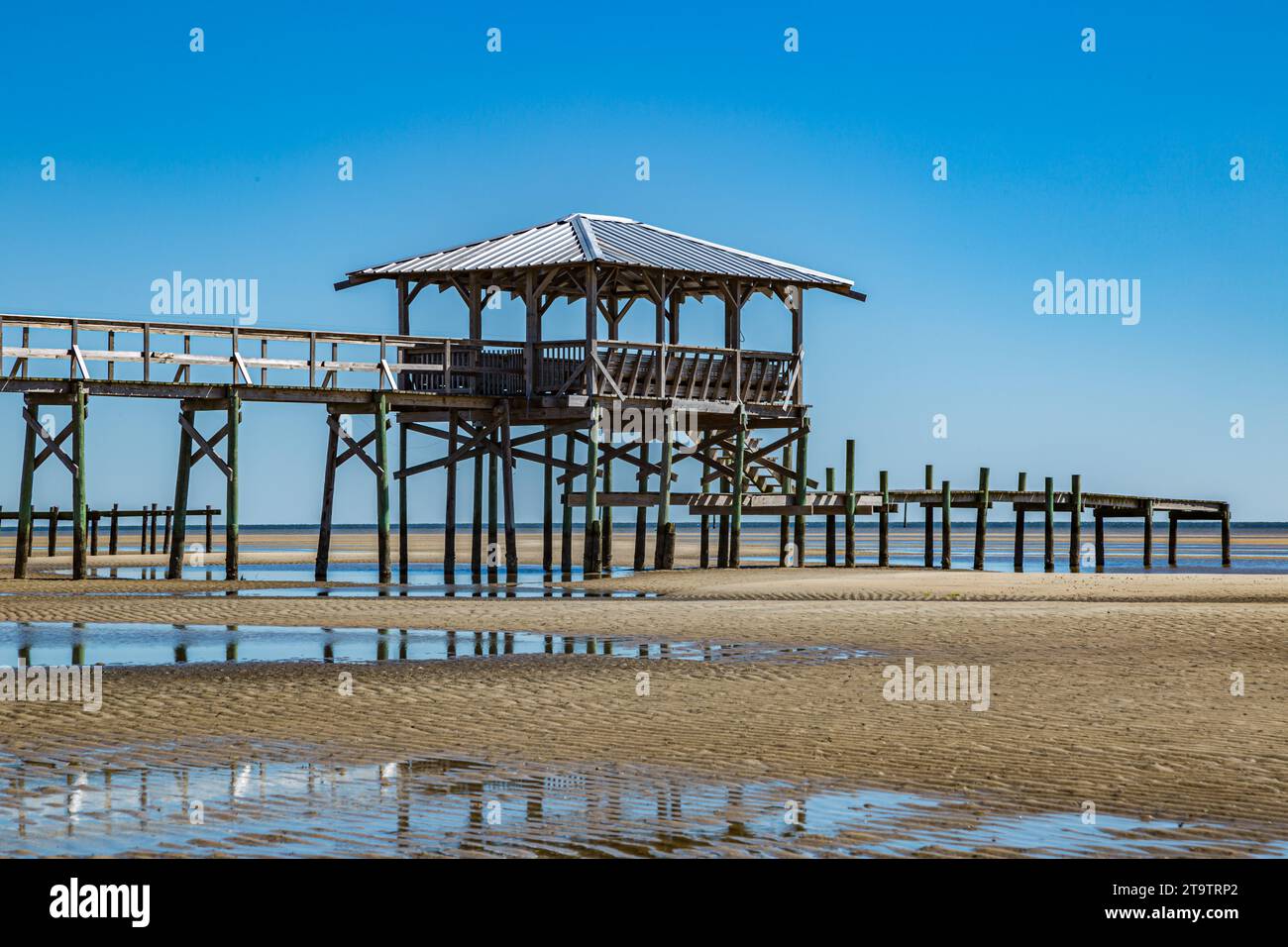 Vieux quai en bois délabré, hangar à bateaux, et jetée se dresse au-dessus des piscines de marée sur la plage de Waveland, Mississippi à marée basse. Banque D'Images