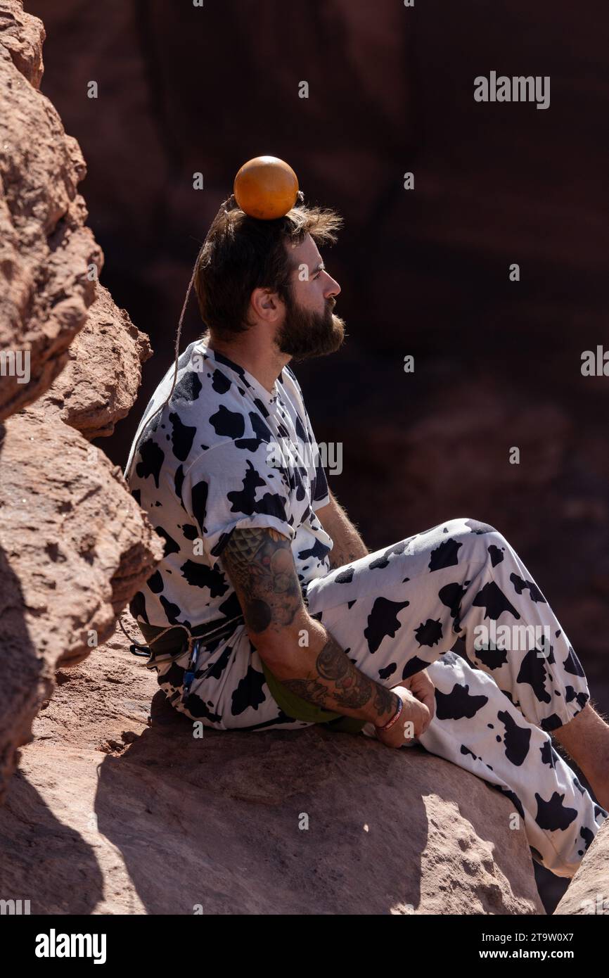 Un participant en costume équilibre un pamplemousse sur sa tête au GGBY Highline Festival à Moab, Utah. Banque D'Images
