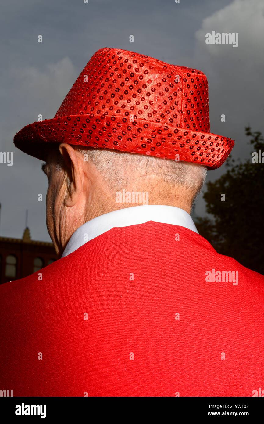 Homme, vu de derrière, en costume rouge vif et chapeau. Banque D'Images