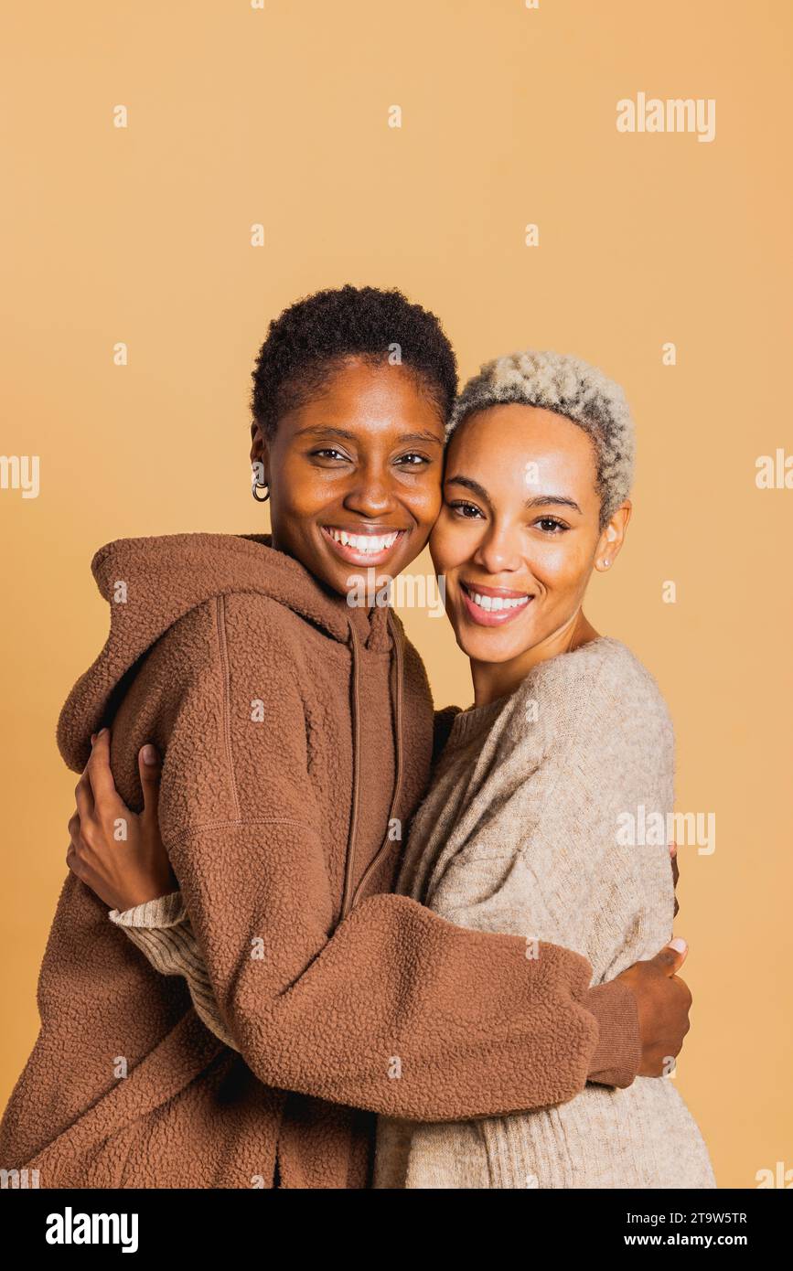 Portrait de deux jeunes femmes afro-américaines embrassant sur fond brun. Jeune couple féminin ensemble. Banque D'Images