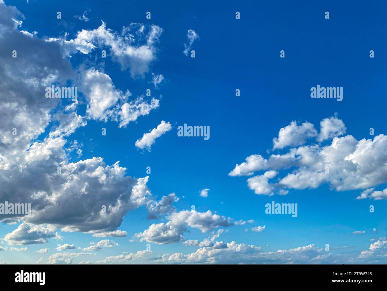 Un ciel bleu avec des nuages blancs au-dessus d'une baie d'eau. Banque D'Images