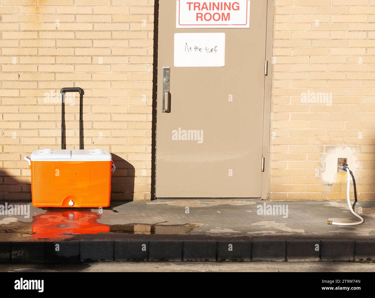 Une glacière orange et blanche assise devant un bâtiment en briques. Banque D'Images