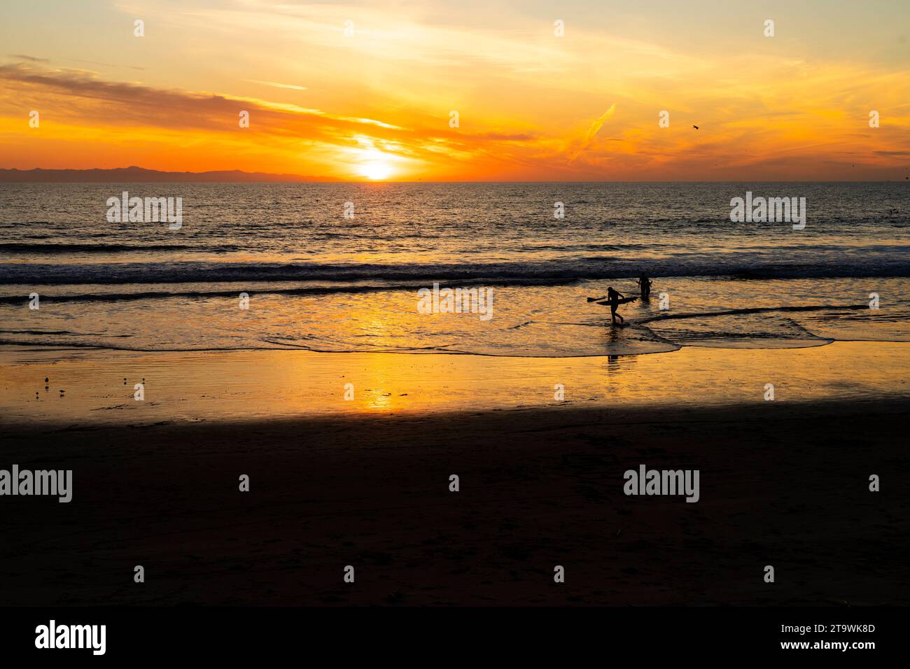 Surf Surfers au coucher du soleil sur une plage californienne Banque D'Images