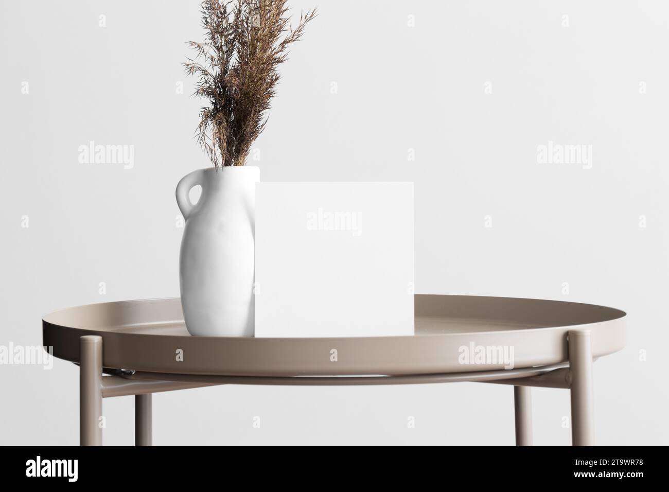 Maquette de carte d'invitation carrée avec une décoration de fleurs séchées sur la table beige. Banque D'Images