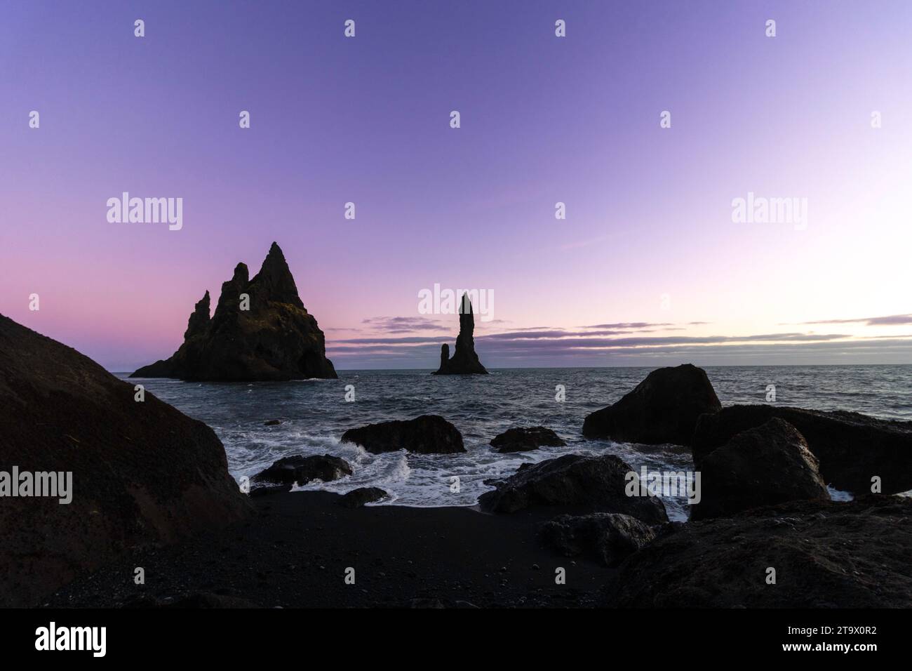 Coucher de soleil sur la plage de Reynisfjara. Plage de sable volcanique noir. Les rochers Reynisdrangar ou les trolls de pierre de Vík. Banque D'Images