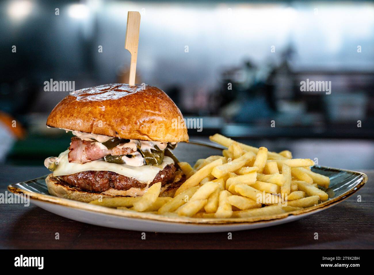 Un cheeseburger angus grillé rempli de bacon et servi avec des frites. Banque D'Images