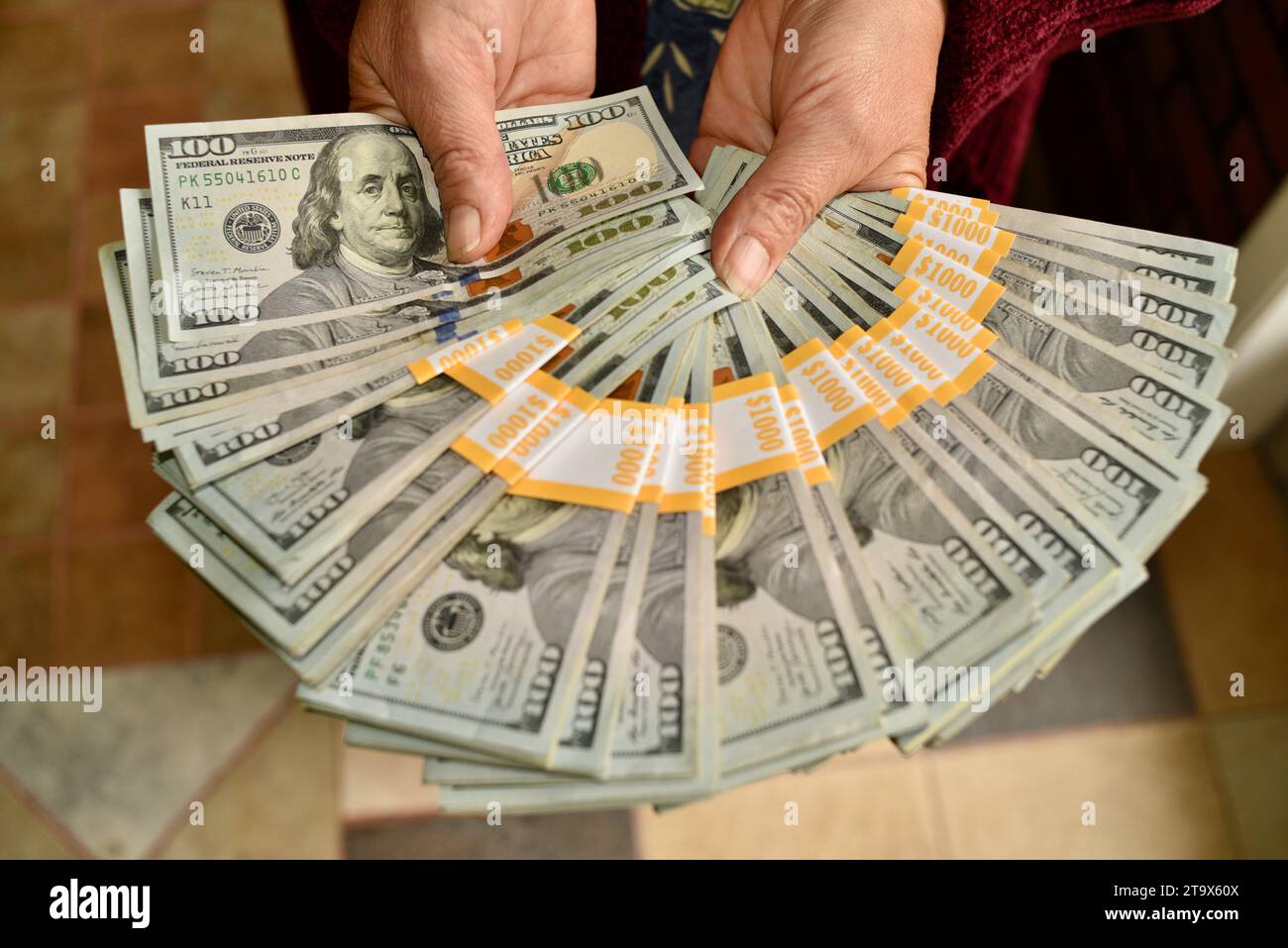 Real $23 000 US dollars, en billets de 100 $ en monnaie comptant, organisé et enveloppé avec des bandes de banque de $1 000, étant attisé dans les mains, Browntown WI, USA Banque D'Images