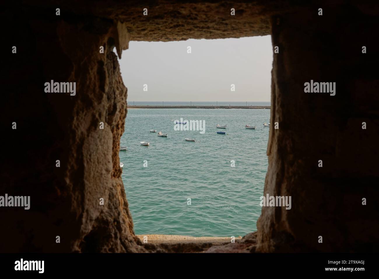 Vue sur la baie de Cadix et les petits bateaux de pêche de l'intérieur du Castillo de Santa Catalina à Cadix, Espagne. Le château en forme de pentagone a été construit après que les Anglais aient saccagé la ville en 1596 pour garder la baie de Cadix. Banque D'Images