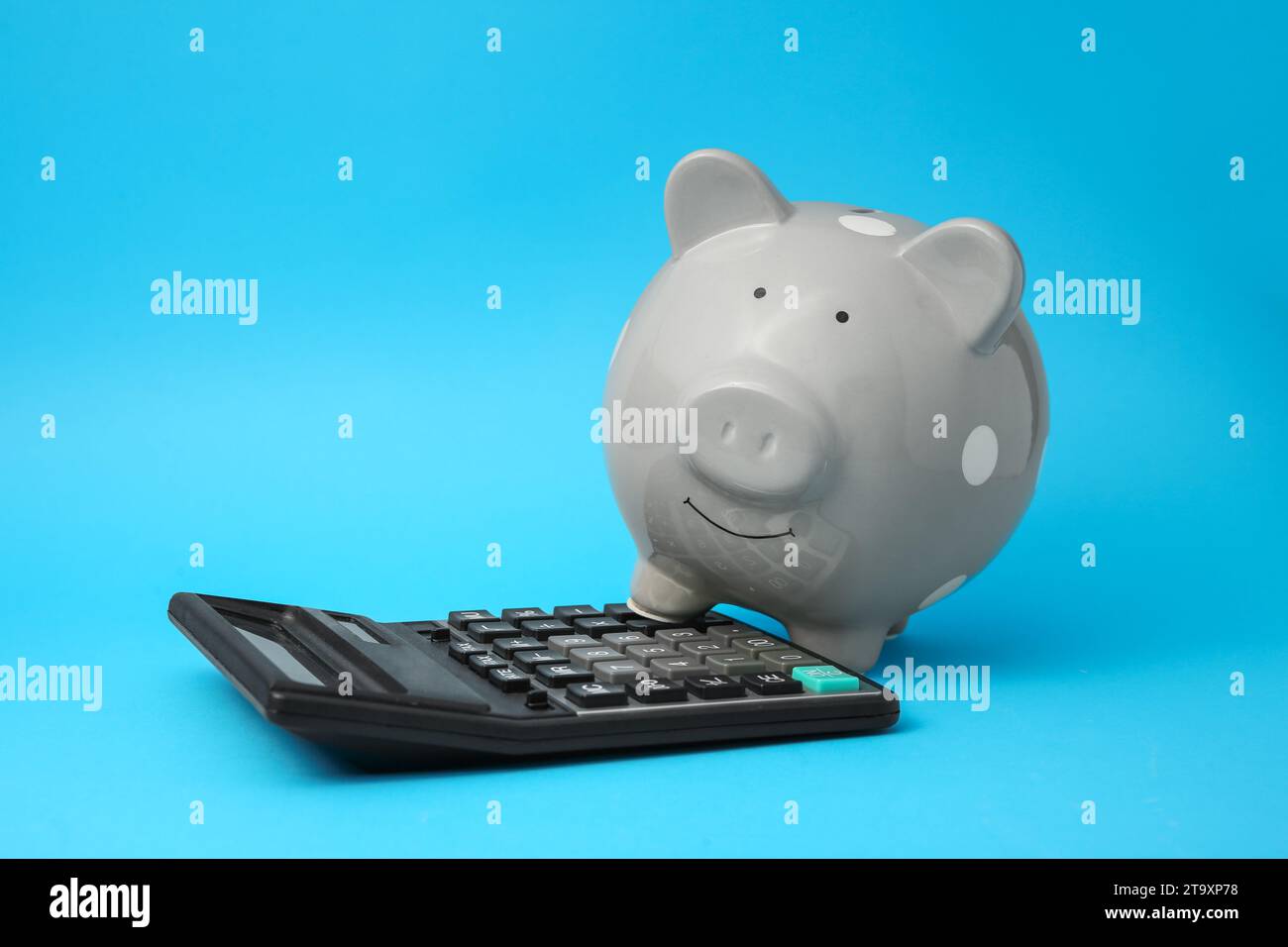 Tirelire et calculatrice sur fond bleu clair Banque D'Images