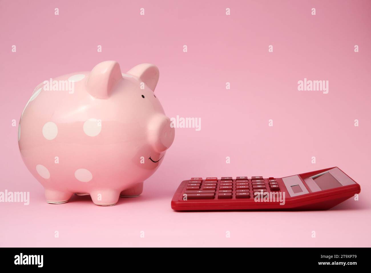 Tirelire et calculatrice sur fond rose Banque D'Images