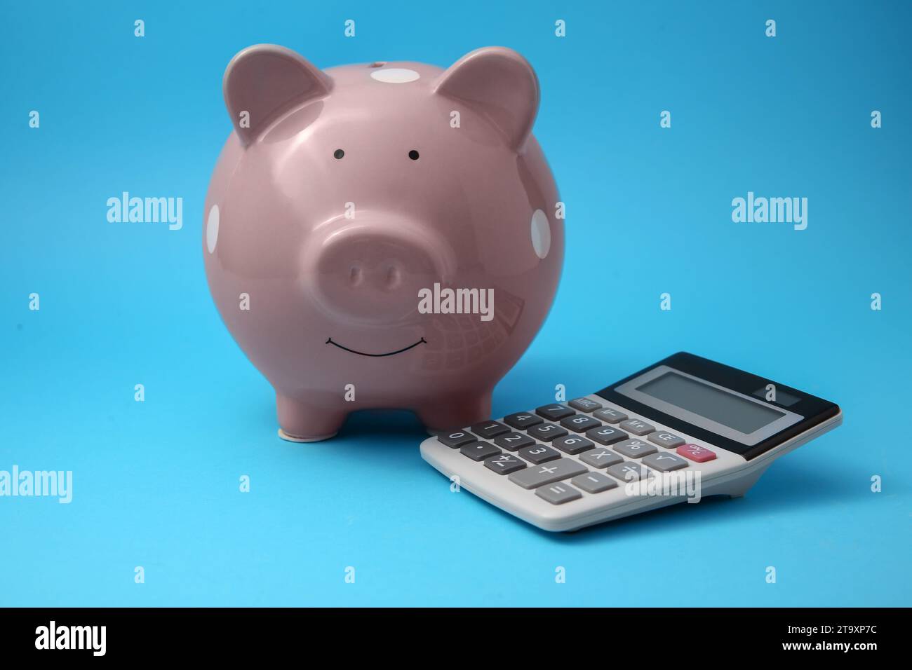 Tirelire et calculatrice sur fond bleu clair Banque D'Images