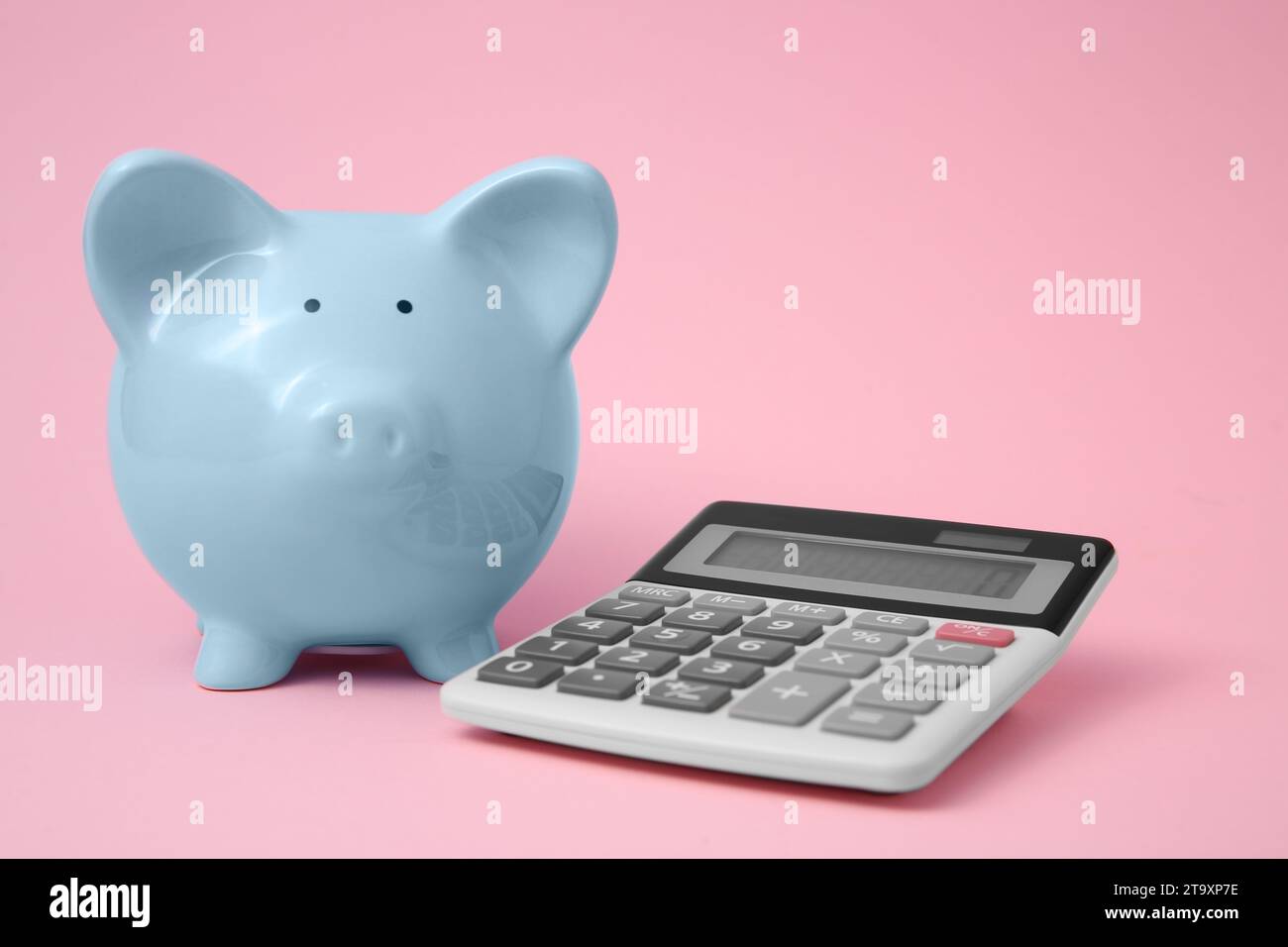 Tirelire et calculatrice sur fond rose Banque D'Images