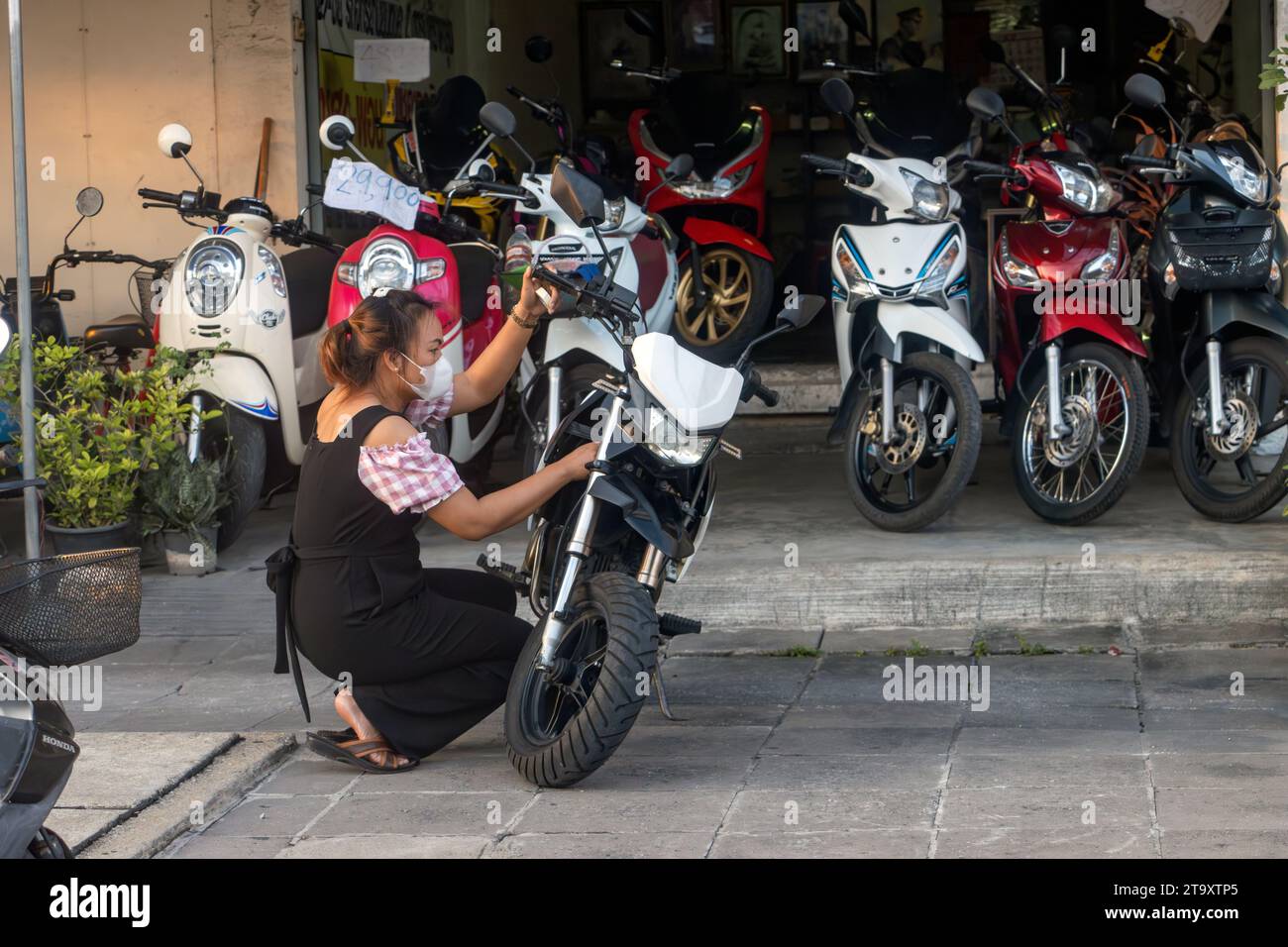 SAMUT PRAKAN, THAÏLANDE, NOVEMBRE 11 2023, Une femme entretient une moto dans la rue devant un magasin de motos Banque D'Images