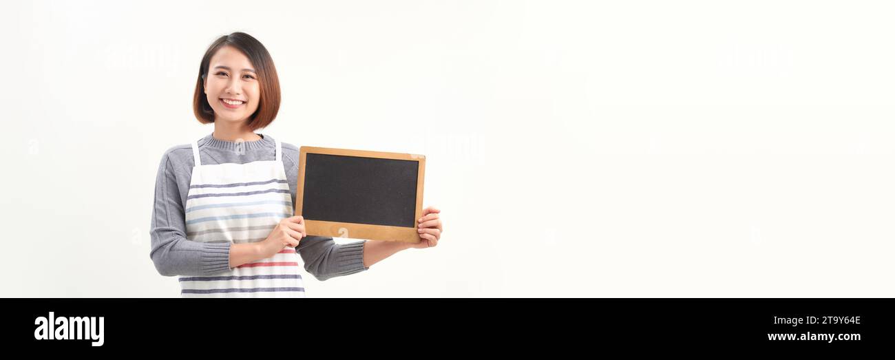 Belle femme en tablier de barista tenant un tableau noir vide sur fond blanc isolé Banque D'Images