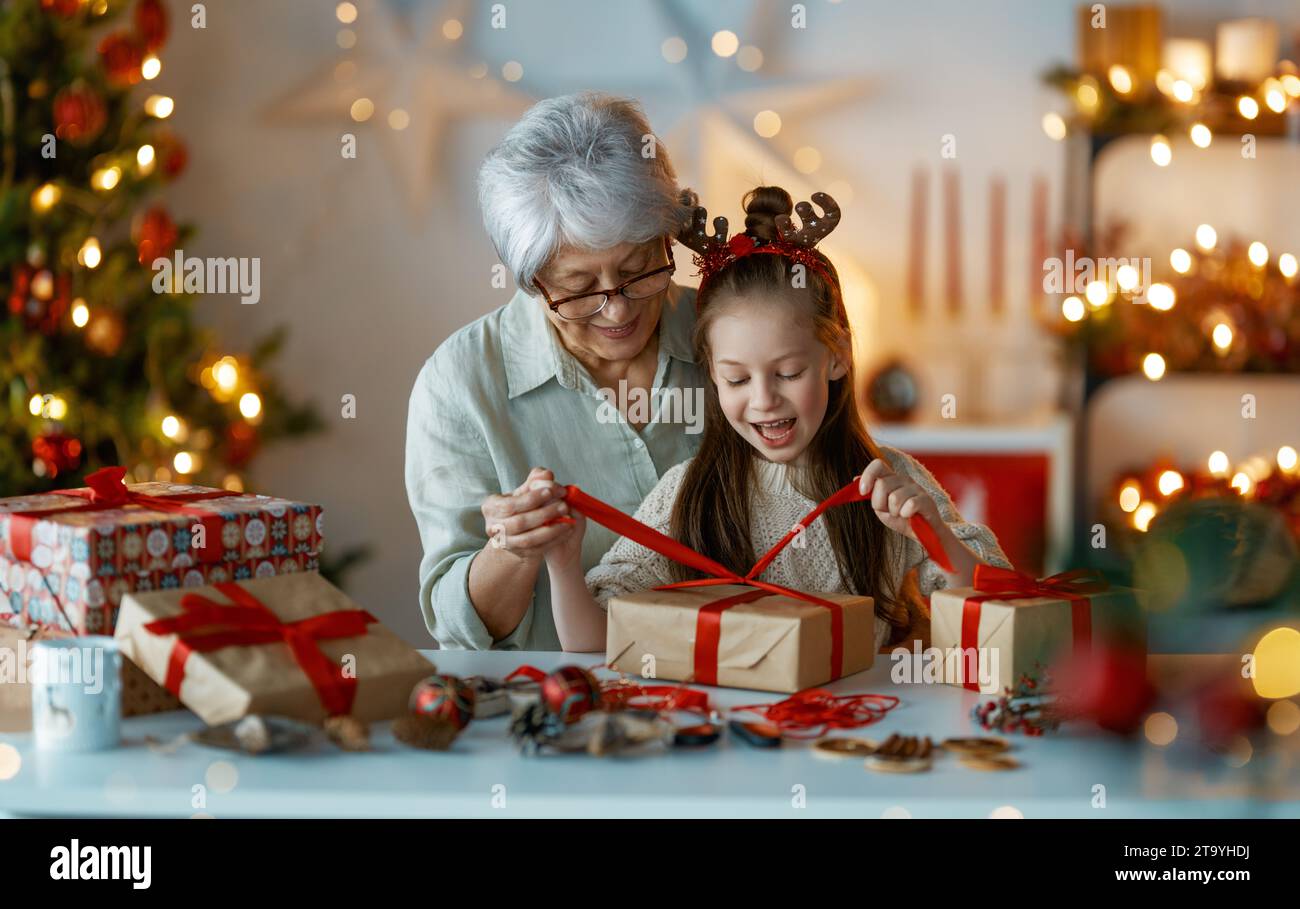 Joyeuses fêtes. Joyeuse grand-mère et sa mignonne petite-fille se préparant pour Noël. Les gens emballent des cadeaux, décorent la maison. Famille aimante wi Banque D'Images