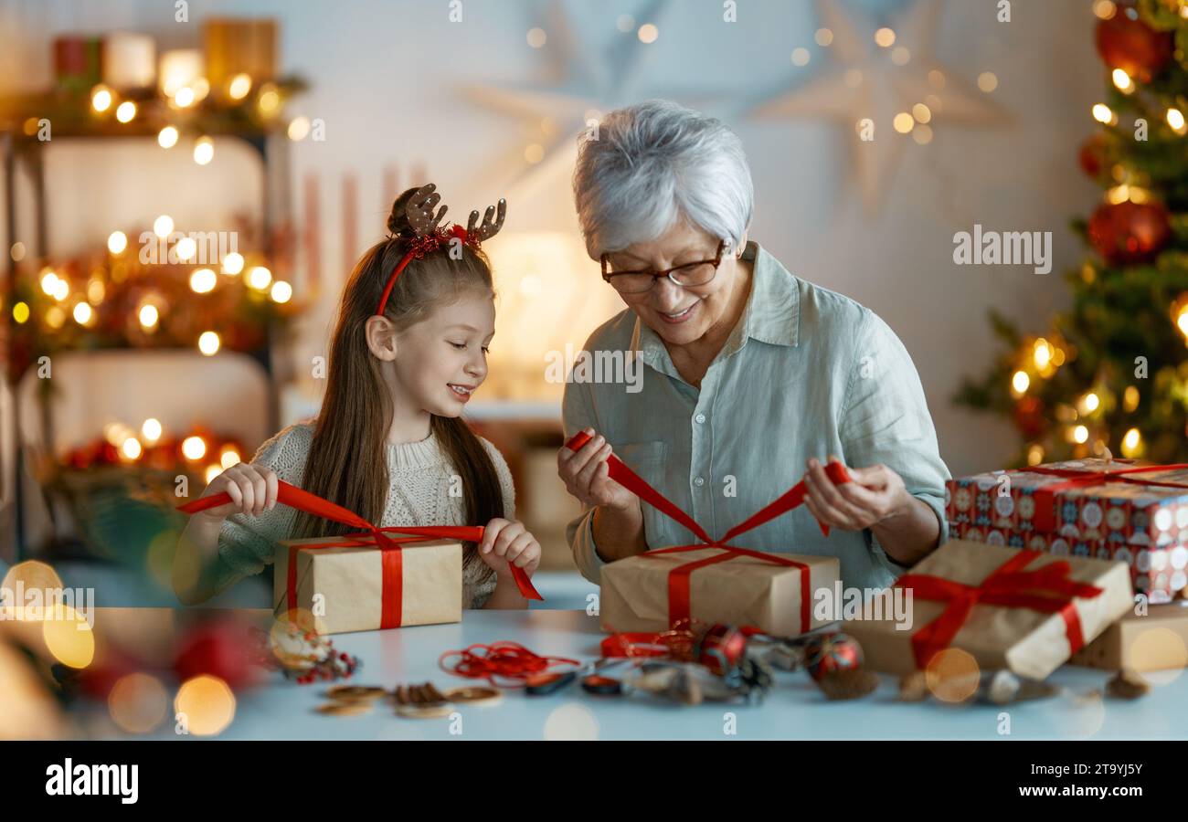 Joyeuses fêtes. Joyeuse grand-mère et sa mignonne petite-fille se préparant pour Noël. Les gens emballent des cadeaux, décorent la maison. Famille aimante wi Banque D'Images