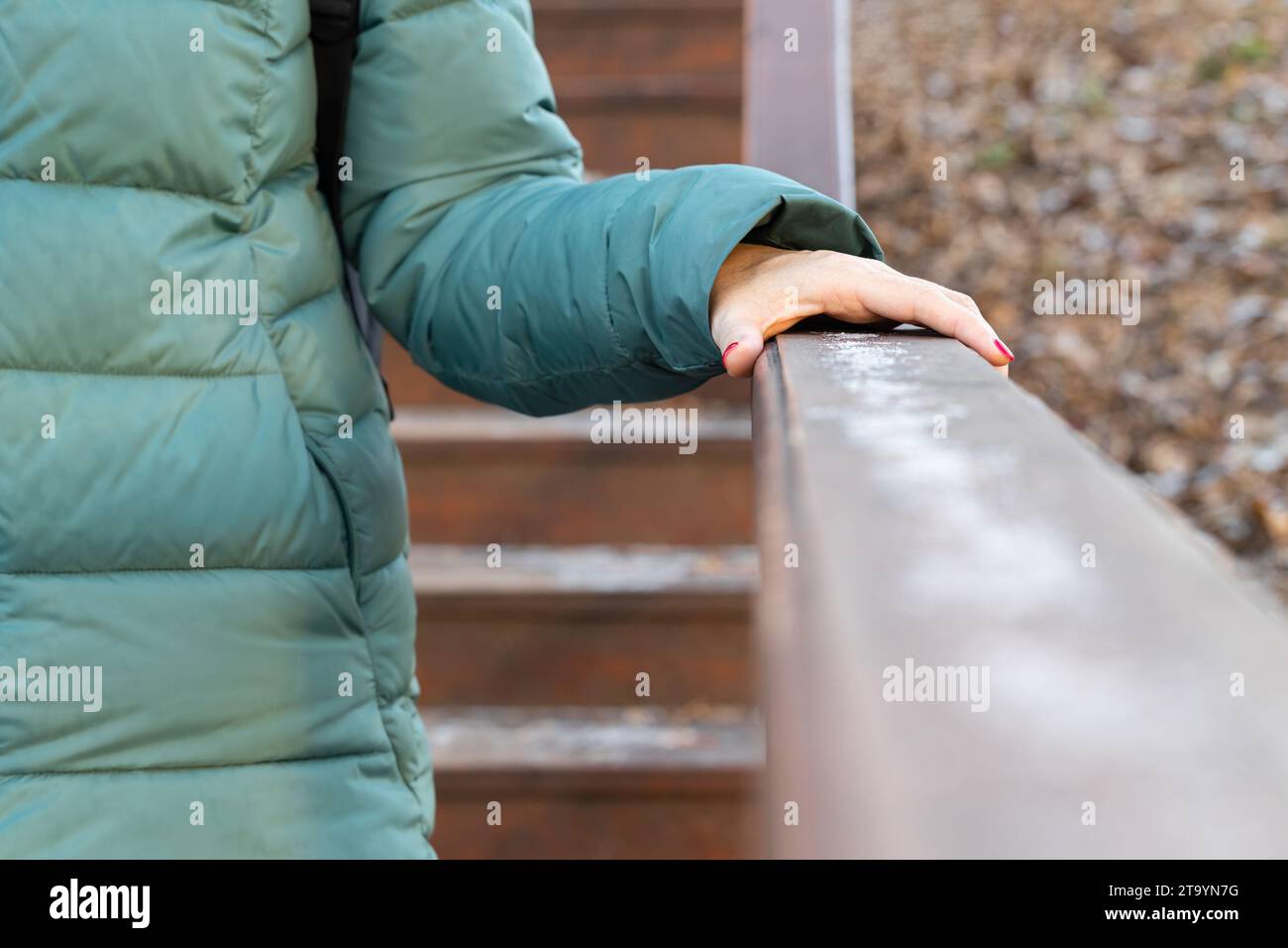 femme tenant sur la main courante en bois par temps pluvieux, tiré avec une faible profondeur de champ. homme descendant les escaliers sous la pluie. Banque D'Images