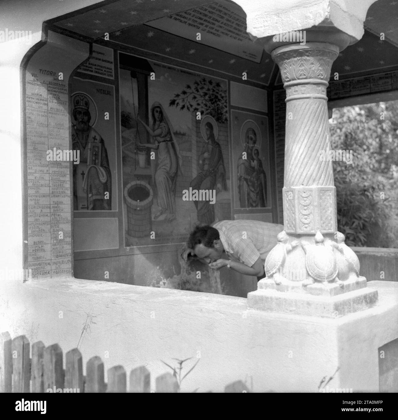 Roumanie, env. 1977. Homme buvant de l'eau d'une source publique dans un monastère. Banque D'Images
