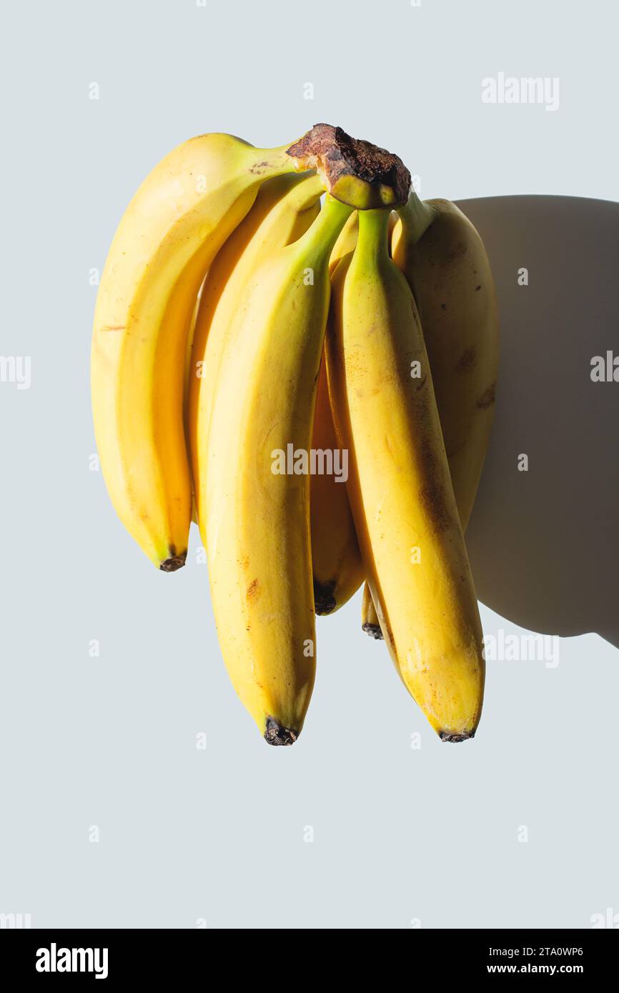 Un bouquet de bananes sur une table blanche au soleil. Banque D'Images