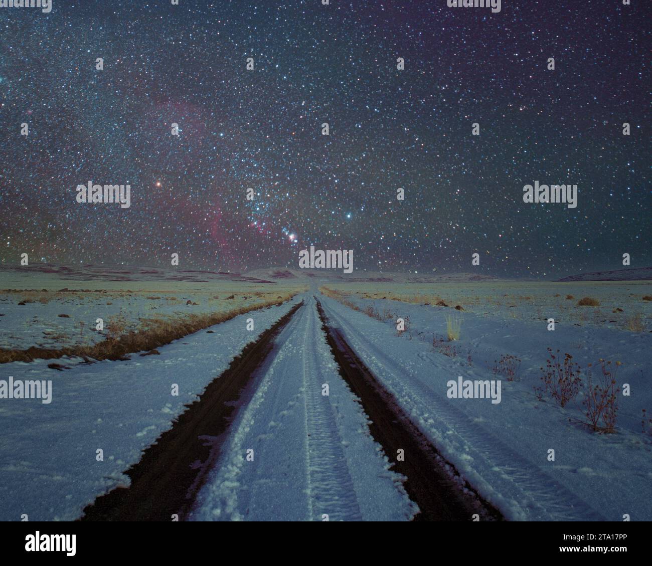 Nightscape avec un chemin de terre enneigé et la constellation d'Orion dans le comté de Lassen, Californie, États-Unis. Banque D'Images