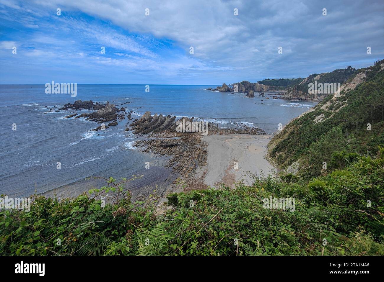 crique de plage rocheuse avec verdure luxuriante sur les falaises sous un beau ciel bleu Banque D'Images