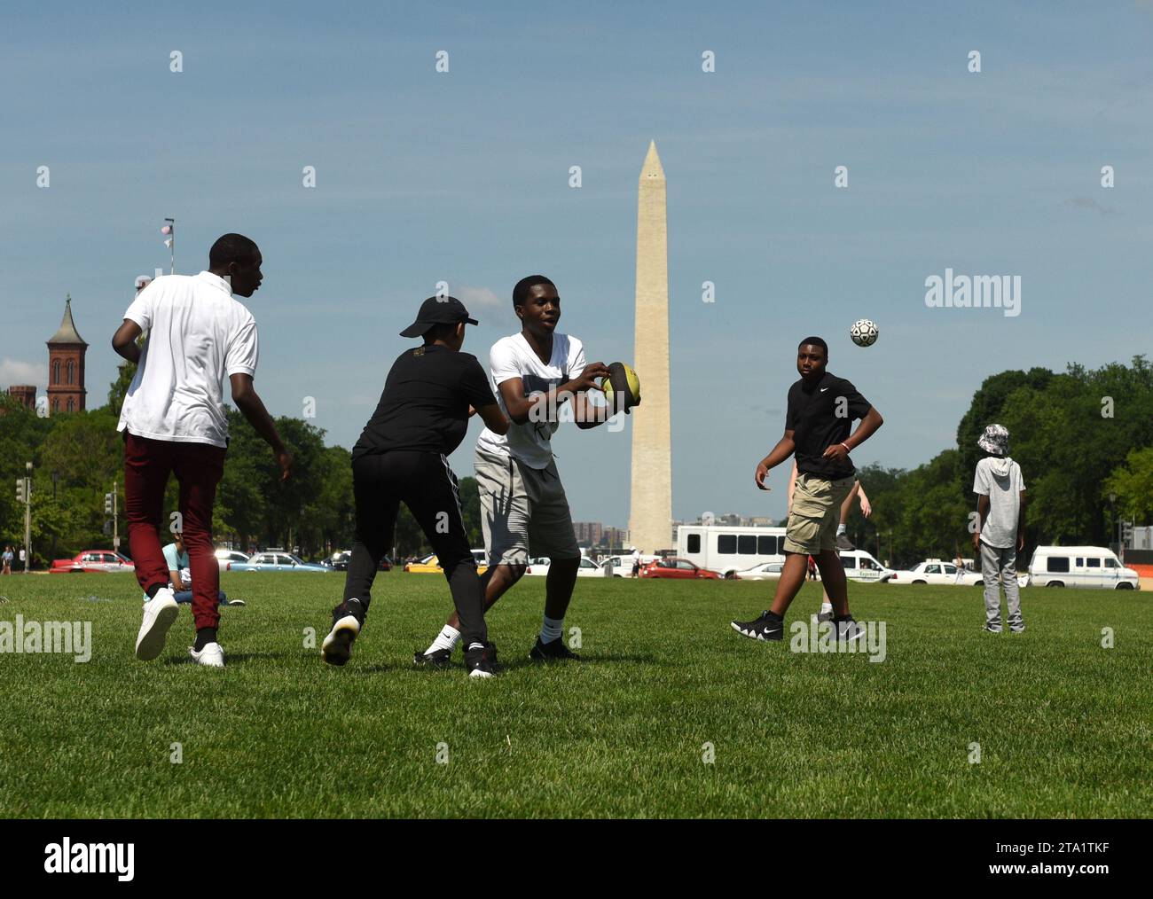 Washington, DC - 01 juin 2018 : les gars jouent le ballon au National Mall avec Washington Monument en arrière-plan à Washington DC, États-Unis Banque D'Images