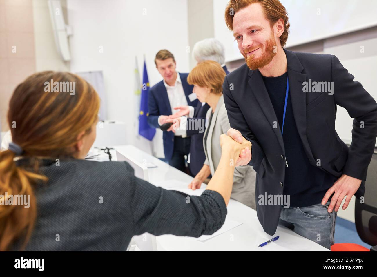 Homme d'affaires souriant poignée de main avec le public féminin sur scène pendant la conférence d'affaires dans l'événement Banque D'Images