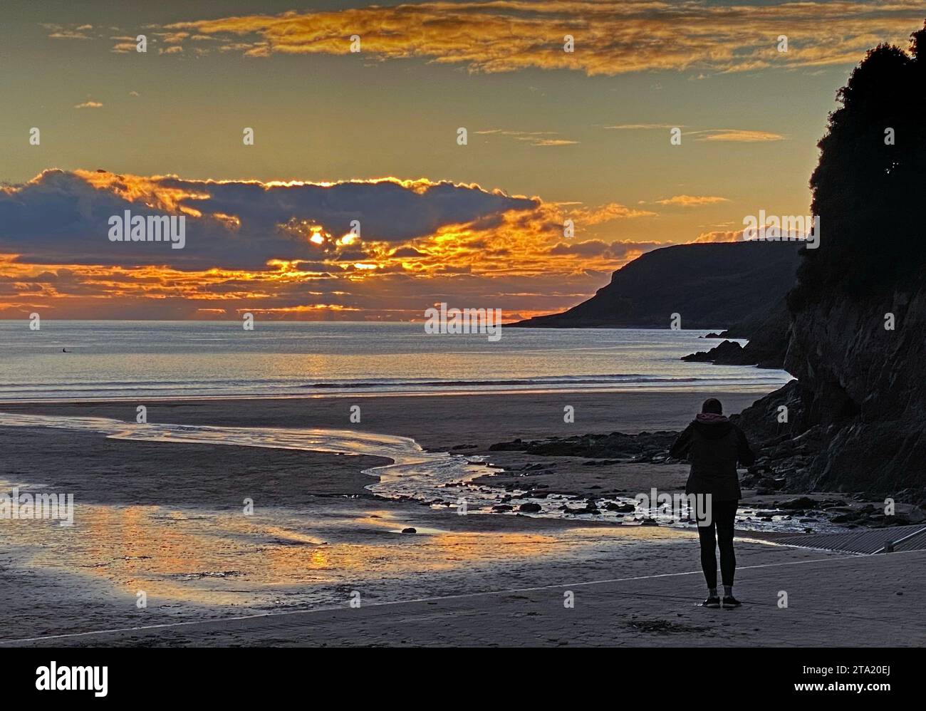 Swansea, Royaume-Uni. 28 novembre 2023. Les gens qui marchent se réchauffent dans le froid alors que le soleil se couche sur Caswell Bay sur la péninsule de Gower près de Swansea ce soir. Crédit : Phil Rees/Alamy Live News Banque D'Images