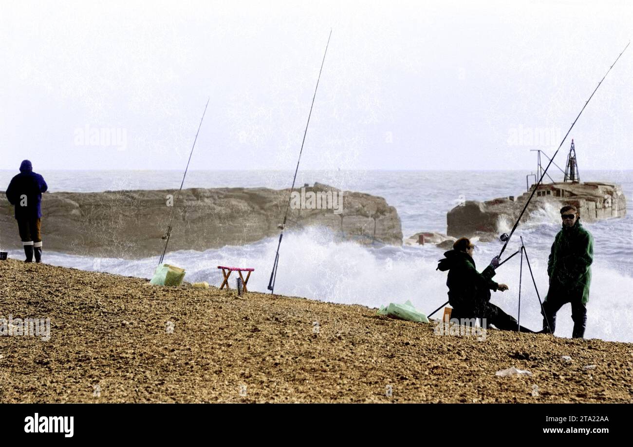 Photo en couleur de BW d'une compétition de pêche sur la plage de Hastings avec le bras du port en arrière-plan en 1971. Banque D'Images