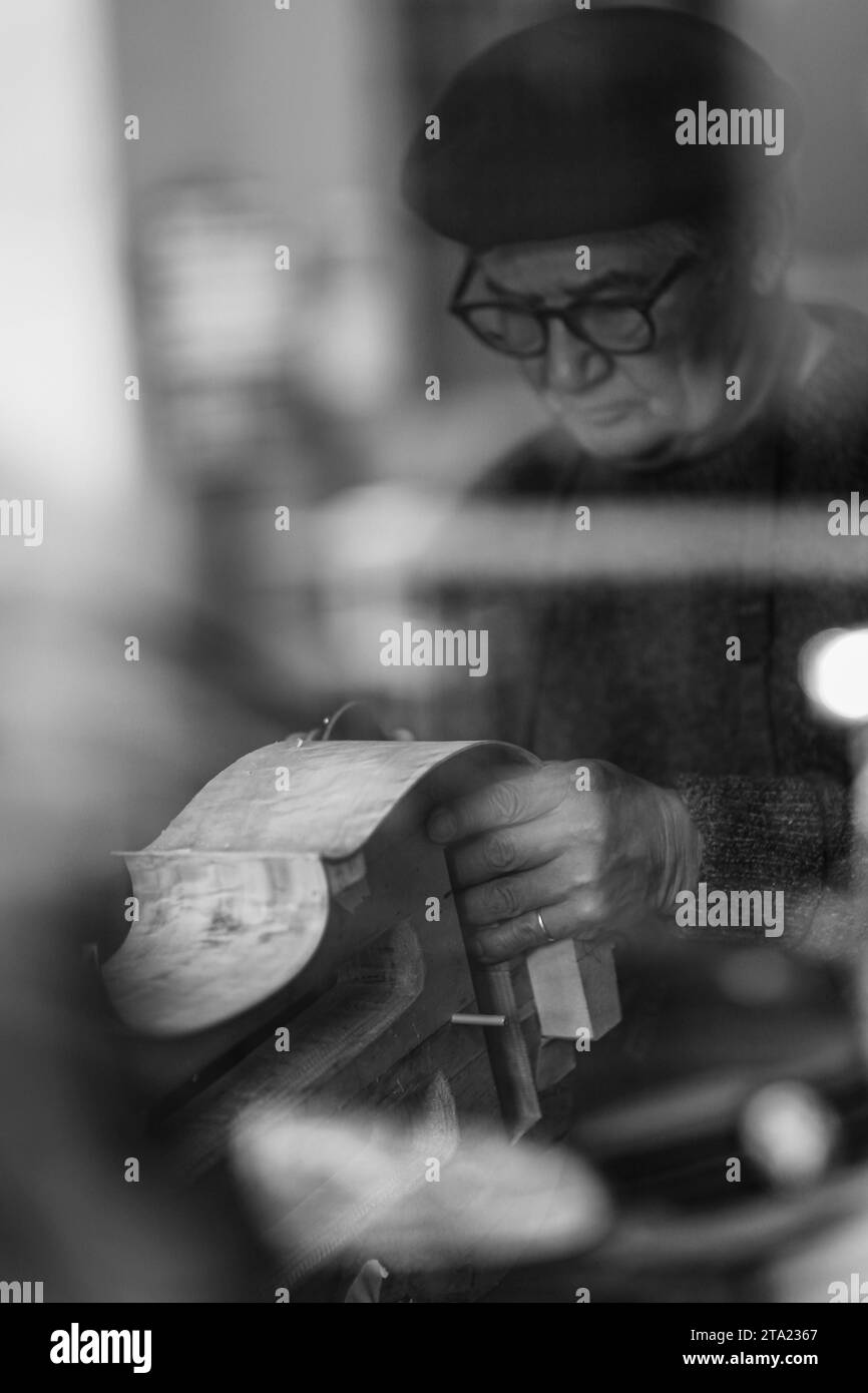 Sénior expet luthier artisan violoncellier sculpter côtelette de nouveau classique dans l'atelier Crémone Italie, mise au point sélective, bokeh, noir et blanc Banque D'Images