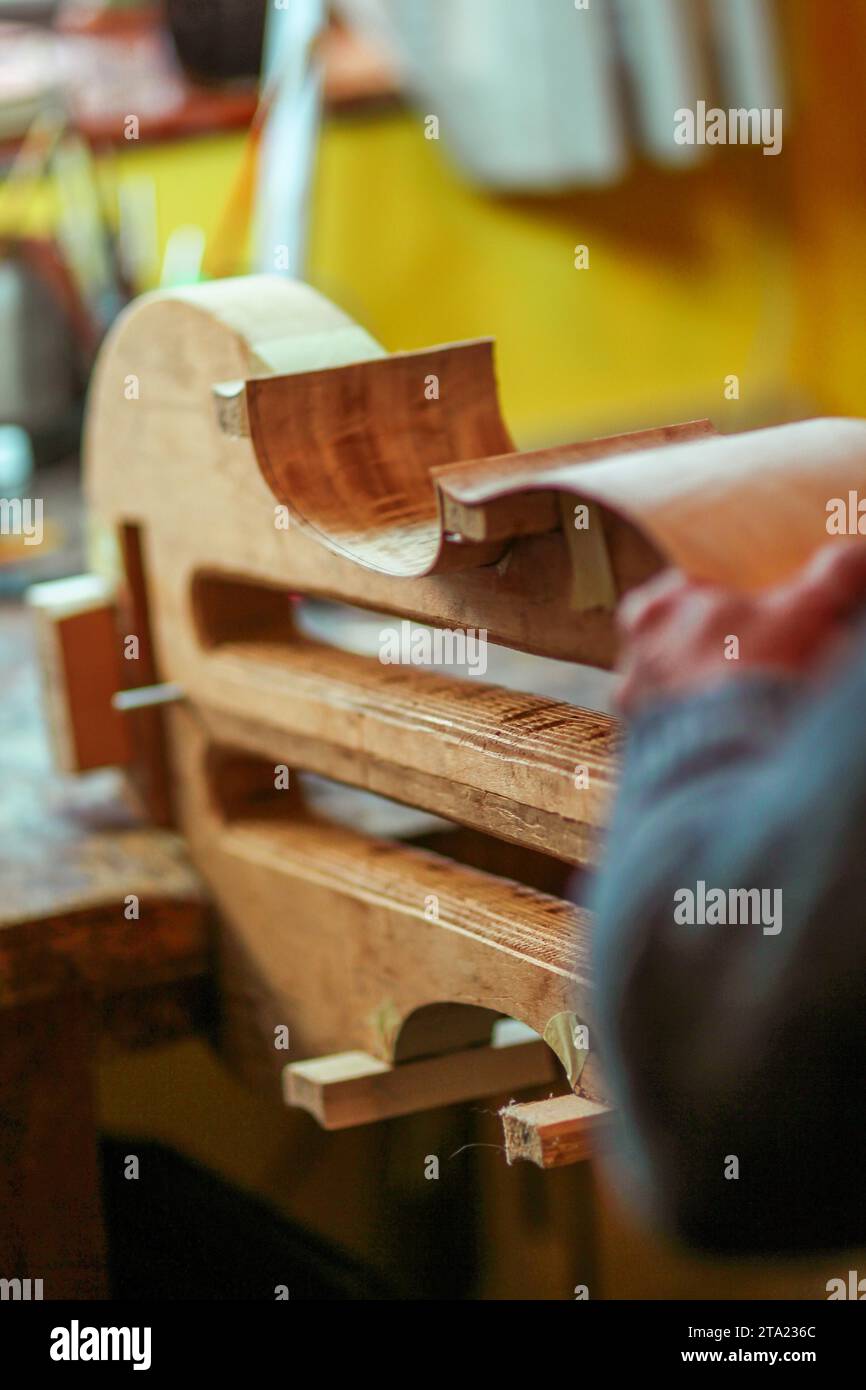 Luthier artisan violoniste sculpter les côtes ciselées d'un nouveau modèle classique violoncelle dans l'atelier Crémone Italie, mise au point sélective, bokeh Banque D'Images