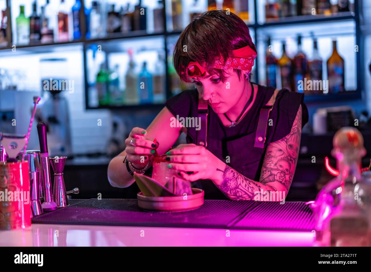 Concentré jeune femme barman décorant un cocktail dans le comptoir de la boîte de nuit Banque D'Images