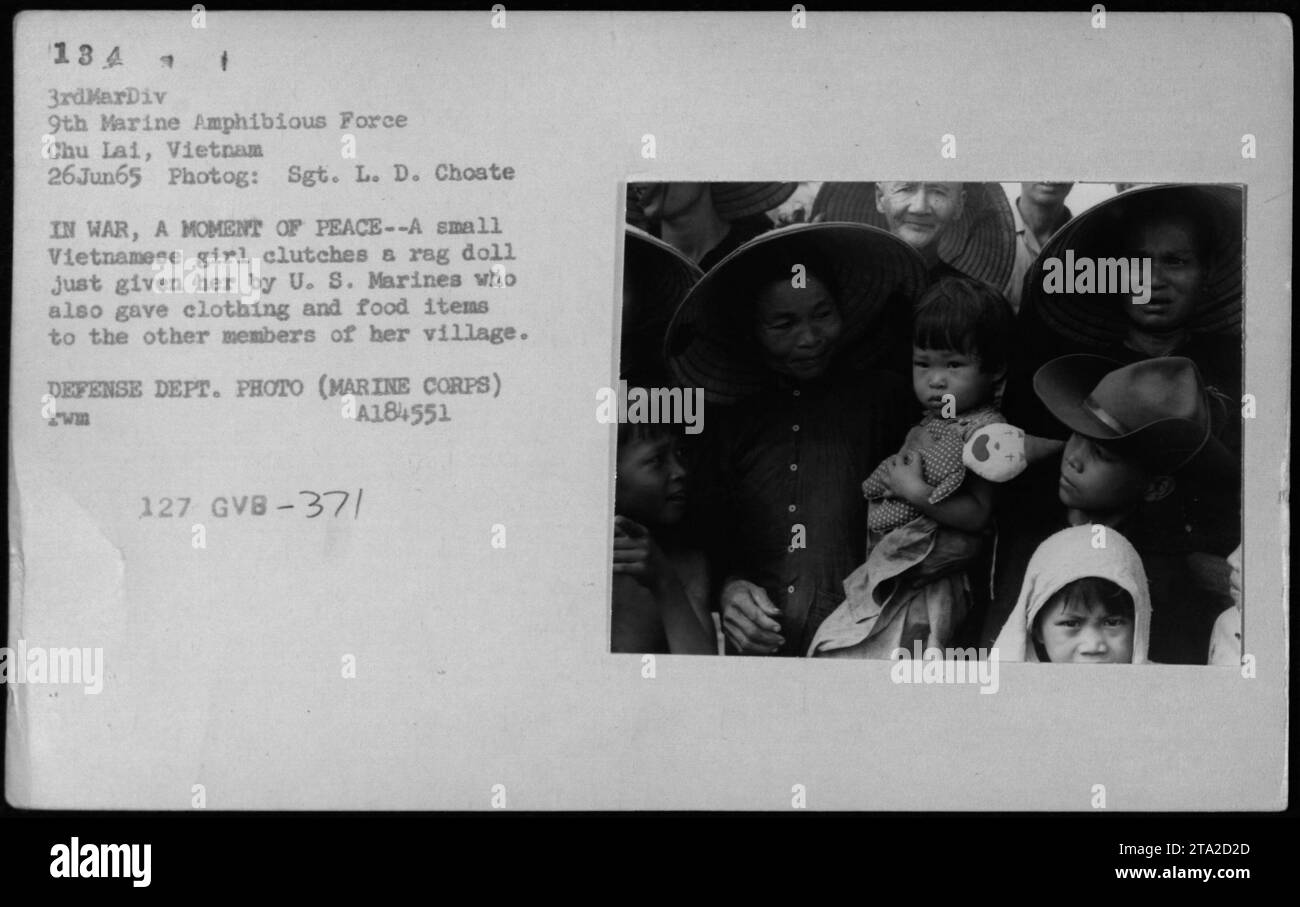 Une jeune fille vietnamienne tient sur une nouvelle poupée de chiffon qui lui a été donnée par les Marines américains. En juin 1965, les Marines à Chu Lai, au Vietnam, distribuèrent des vêtements et des aliments à la jeune fille et à ses camarades villageois, offrant un bref moment de paix au milieu de la guerre. DEPT. DÉFENSE PHOTO (MARINE CORPS) A184551 RHUM 127 GVB-37/ Banque D'Images