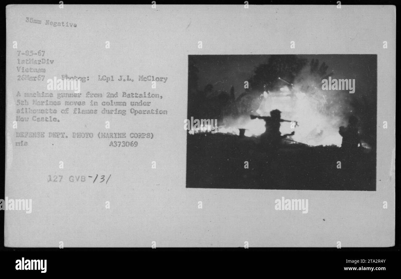 Mitrailleuse du 2e Bataillon, 5e Marines se déplaçant sous la silhouette de flammes lors de l'opération New Castle au Vietnam le 26 mars 1967. Photographie de combat prise par le lcpl J.L. McClory, 1e Division des Marines. Photo officielle du ministère de la Défense (corps des Marines) A373069. Banque D'Images
