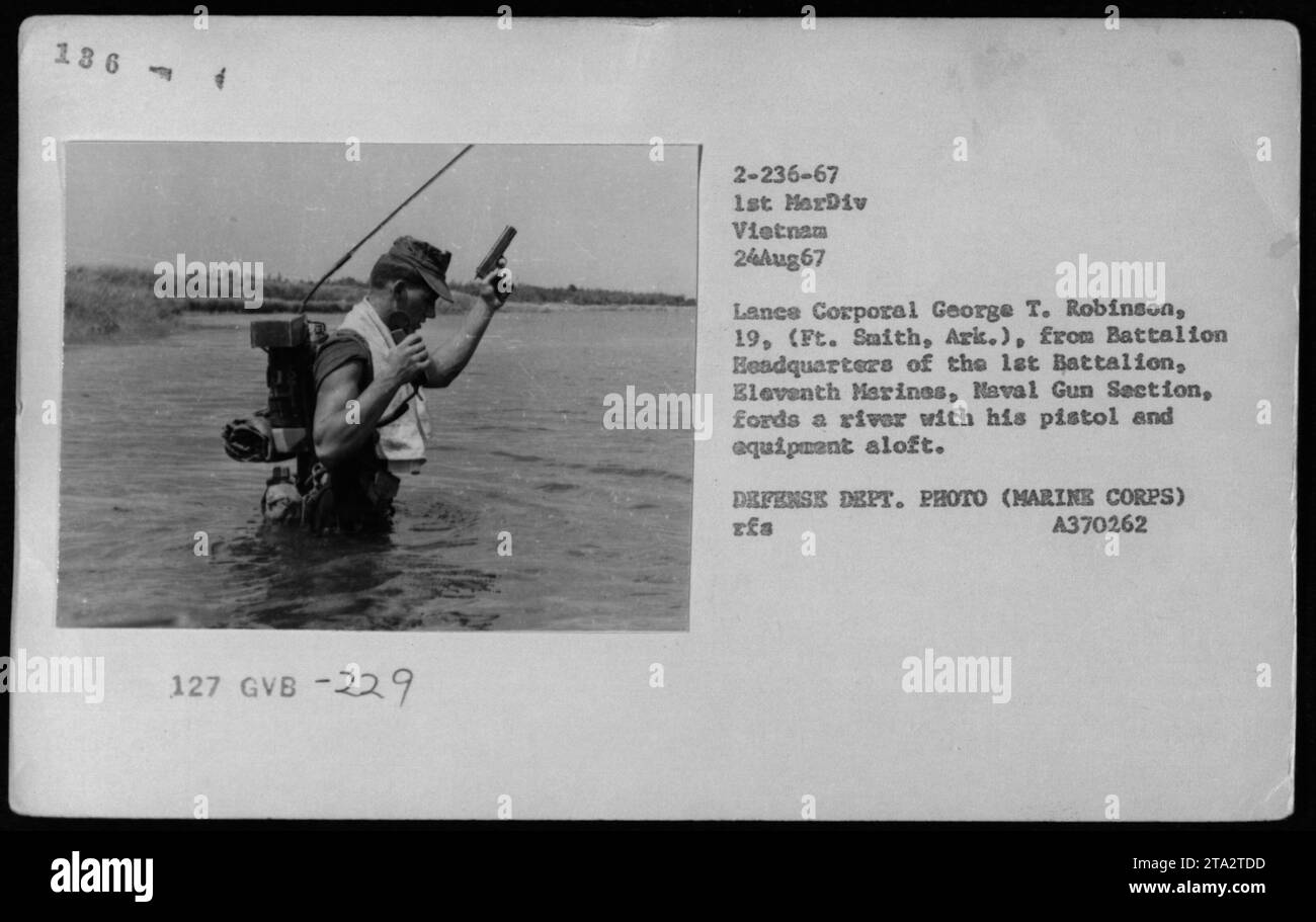 Le caporal-chef George T. Robinson du 1e Bataillon, onzième Marines, Section des canons de la Marine, est vu à gué sur une rivière au Vietnam le 24 août 1967. Il porte son pistolet et son équipement en altitude pendant qu'il navigue dans les eaux. Cette photographie a été prise par le ministère de la Défense et appartient aux archives du corps des Marines. Banque D'Images