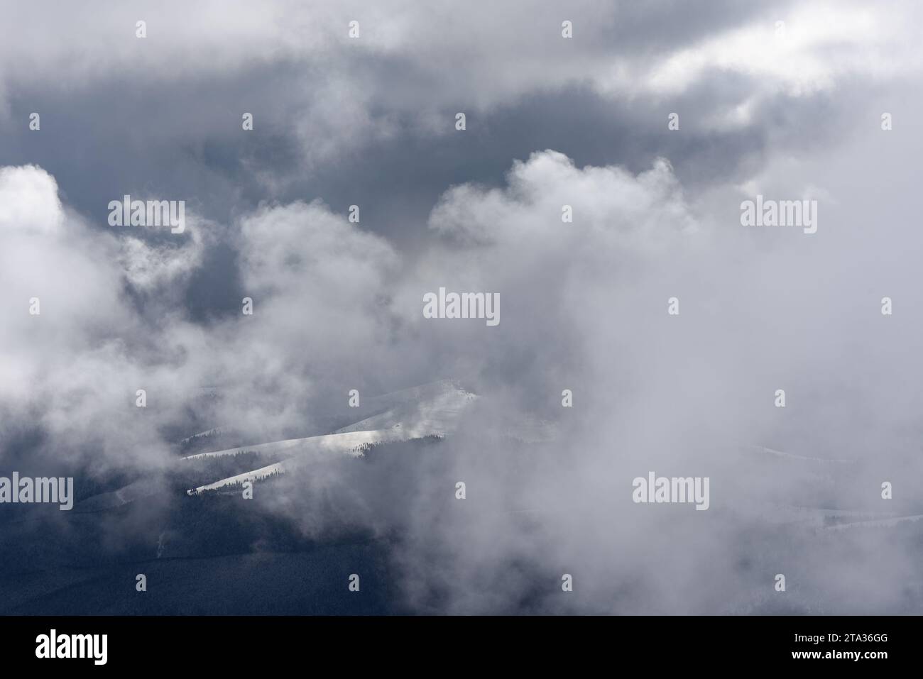 Paysage d'hiver avec des nuages suspendus bas dans les montagnes et la vallée enveloppé dans la brume Banque D'Images