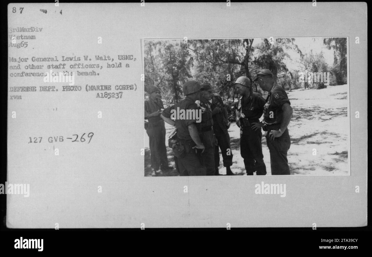 Pendant la guerre du Vietnam en août 1965, le major-général Lewis W. Walt, USMC, et d'autres officiers d'état-major sont photographiés lors d'une conférence sur la plage. Parmi les personnes présentes figurent Robert McNamara, Richard Nixon et Billy Graham. Cette image souligne la présence de ces officiers et fonctionnaires pendant cette période. Banque D'Images