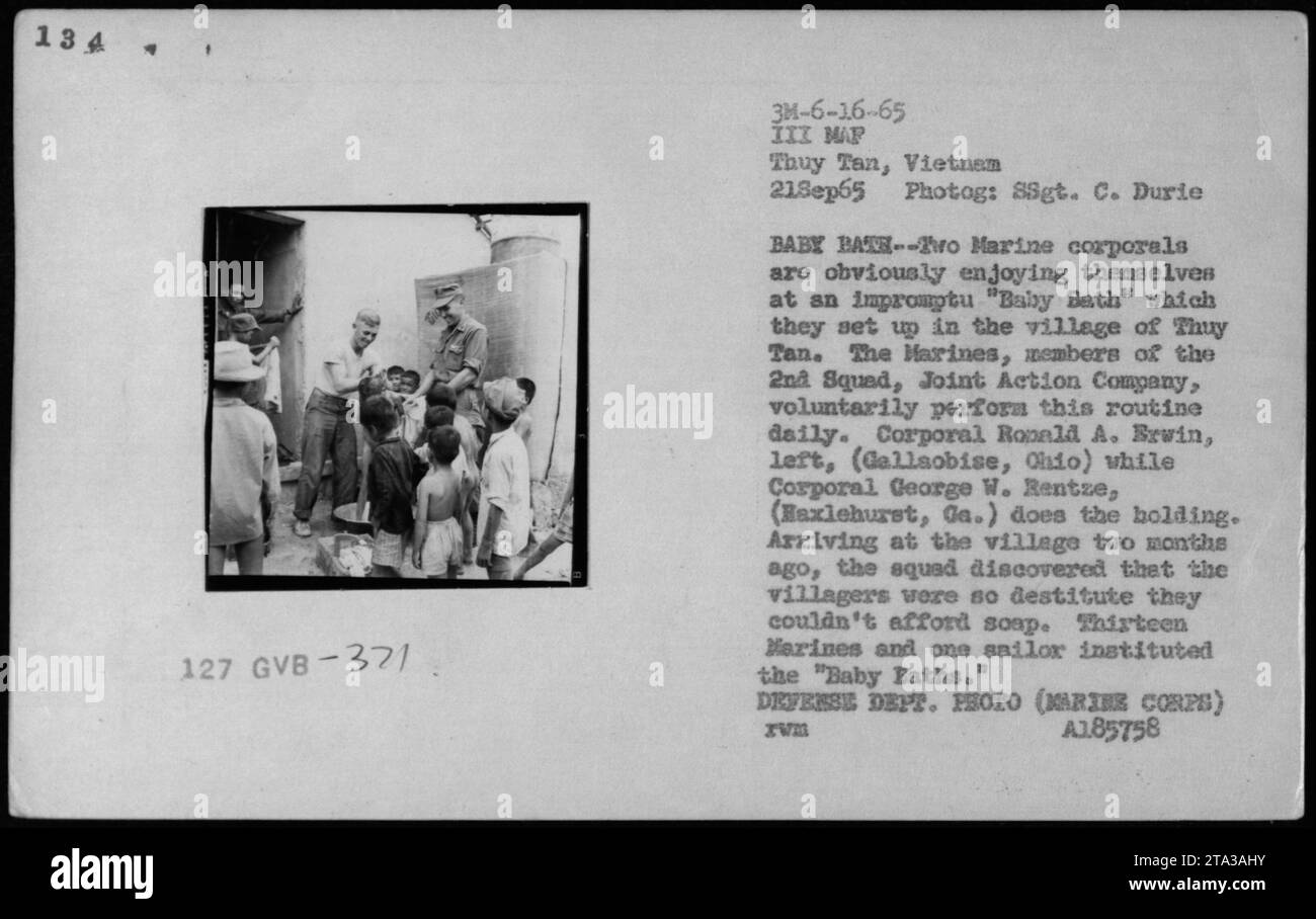 Les caporaux de Marine installent un « Baby Bath » impromptu dans le village de Thuy Tan le 21 septembre 1965. Le caporal Ronald A. Brwin de Gallipolis, Ohio, et le caporal George W. Rentze de Haxlehurst, Géorgie sont vus sur la photo, avec Rentze berçant le bébé. L'escouade a lancé cette routine comme un acte de bonne volonté envers les villageois démunis qui ne pouvaient pas se permettre de savon. Les « bains de bébé » ont été exécutés quotidiennement par treize Marines et un marin de la 2e escouade, joint action Company. Cette image a été prise par le SSgt. C. Durie, et fait partie de l'album American Military Activities de la guerre du Vietnam. Banque D'Images