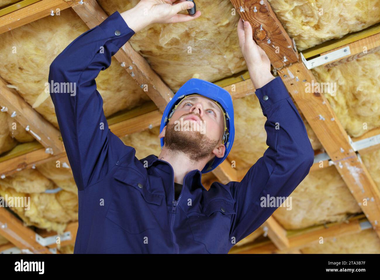 le travailleur de contenu travaille sur le plafond de bois Banque D'Images