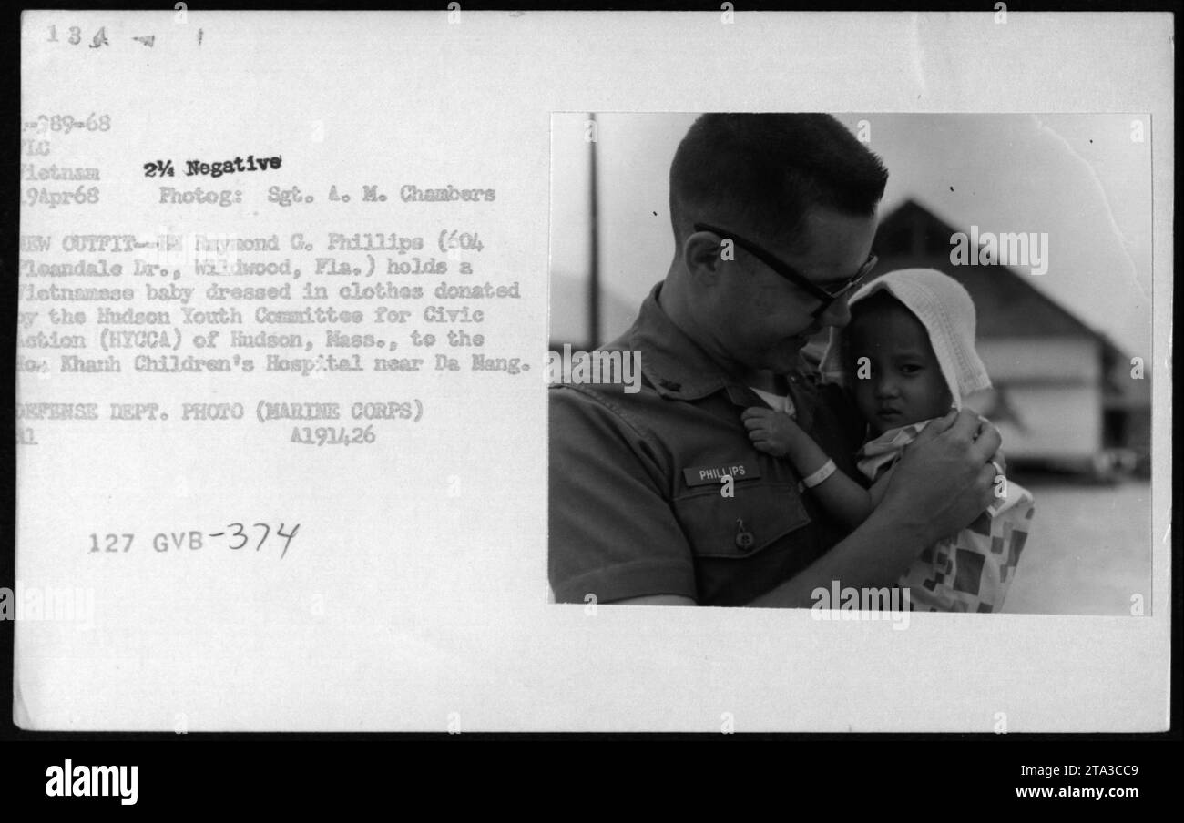 Raymond G. Phillips, membre de l'armée américaine, tient un bébé vietnamien vêtu de vêtements donnés par le Hudson Youth Committee for Civic action (HYCCA) à l'hôpital pour enfants de CoA Khanh près de Da Han. Cette photo a été prise le 19 avril 1968, pendant la guerre du Vietnam. Banque D'Images