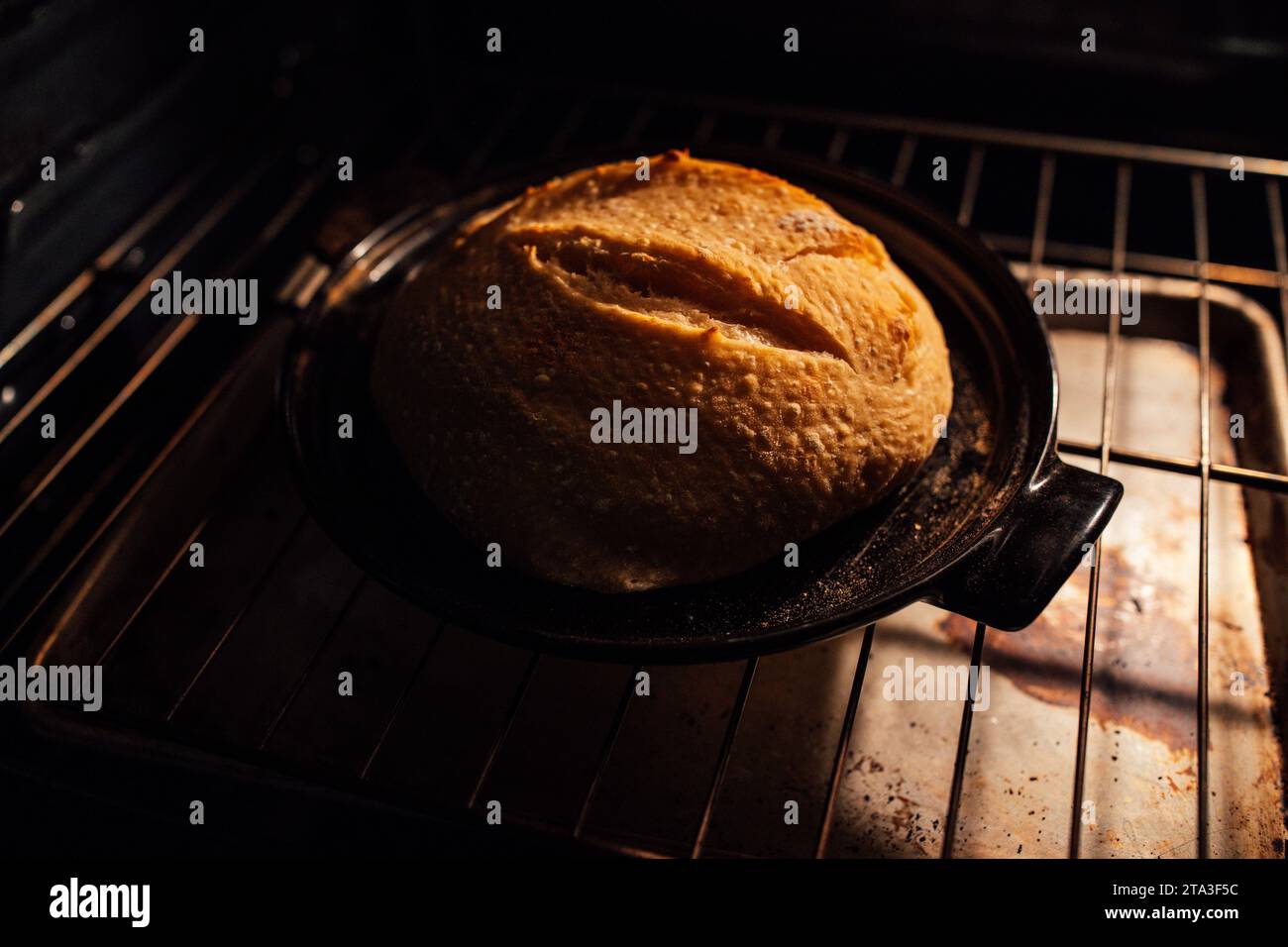 cuisson de boule de levain maison au four sur la partie en céramique noire de cloche de pain Banque D'Images
