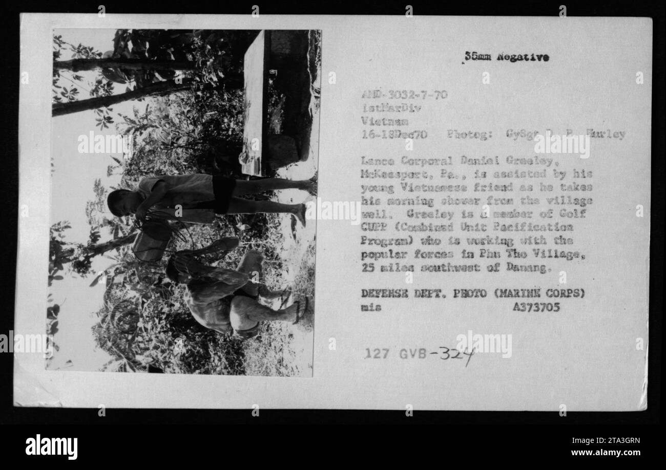 La photographie montre le caporal Daniel Greeley, des US Marines, prenant une douche matinale avec l'aide d'un ami vietnamien à Phu the Village, à 25 milles au sud-ouest de Danang, dans le cadre du CUPP de golf le 16 décembre 1970. Banque D'Images