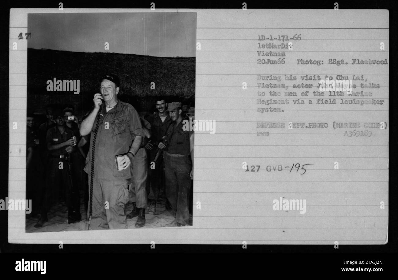 Lors de sa visite à Chu Lai, au Vietnam en juin 1966, l'acteur John Wayne est vu s'adresser aux troupes du 11e Régiment de Marines à travers un système de haut-parleurs de terrain. Cette photo capture l'interaction entre Wayne et les soldats au cours de sa visite divertissante pour élever le moral des troupes stationnées au Vietnam. Banque D'Images