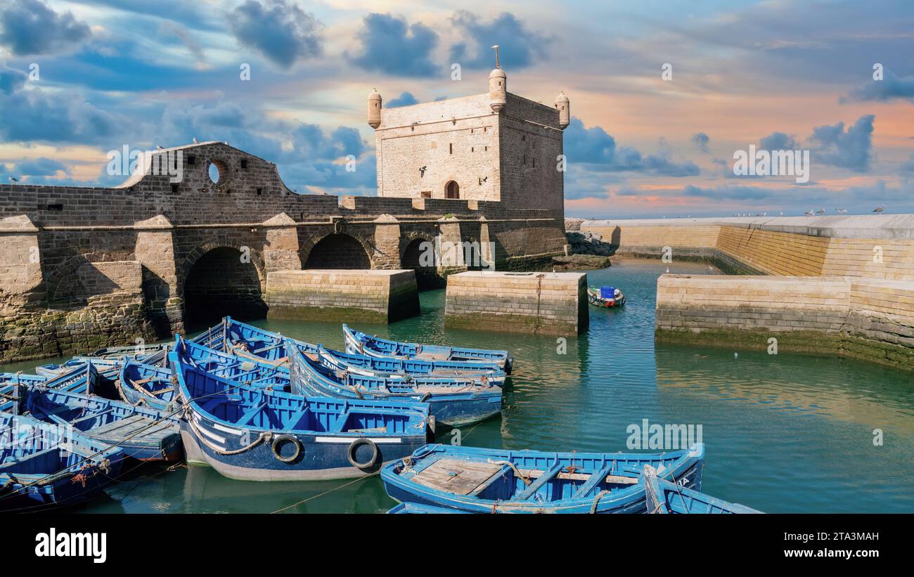 Sqala du Port avec des nuages spectaculaires, une forteresse historique surplombant l'océan Atlantique au port de pêche d'Essaouira avec de nombreuses mouettes survolées Banque D'Images
