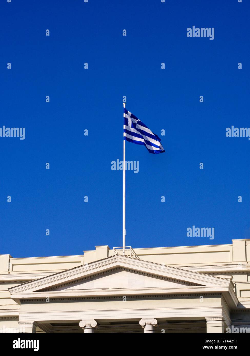 Drapeau grec sur poteau au-dessus du toit du bâtiment classique Banque D'Images