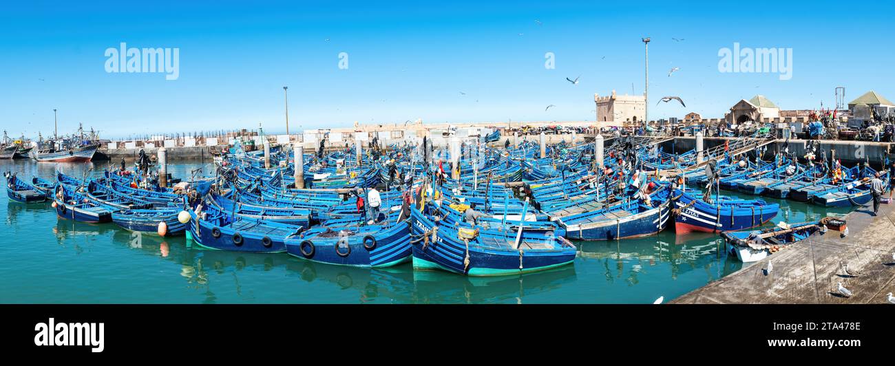 Essaouira, Maroc - 17 septembre 2022 : pêcheurs à bord de bateaux de pêche bleus amarrés au port d'Essaouira. Les bateaux de pêche bordent le port, amenant dans la da Banque D'Images
