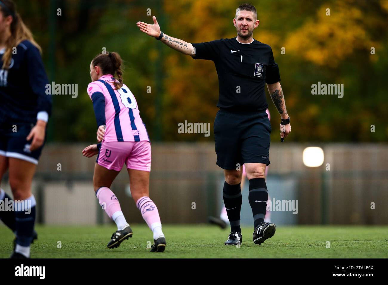 Un arbitre masculin signale un coup franc pendant un match de football féminin Banque D'Images
